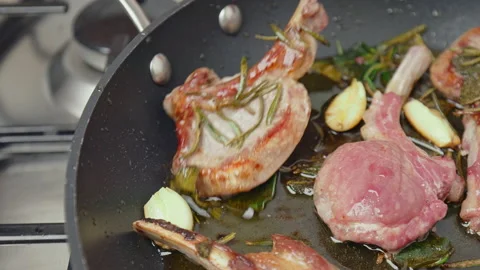 Close-up turning on the other side lamb ribs cutlets in a frying pan with greens Stock Footage 145999671