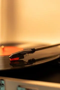 Close-up of a turntable needle playing a vinyl record with warm lighting Stock Photos