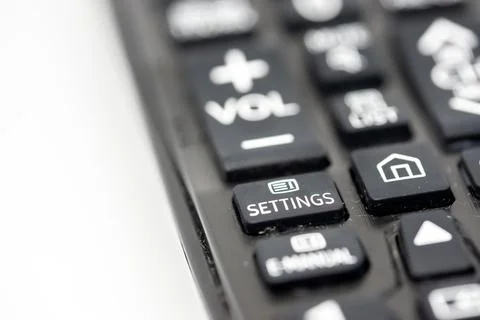 Close-up of a TV remote control with focus on the settings button Stock Photos