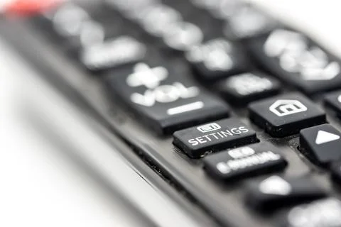 Close-up of a TV remote control with focus on the settings button Stock Photos
