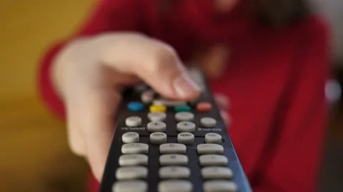 Close-up of TV remote control in the hands of a child who switches TV channel Stock Footage 228806949