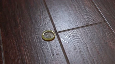 Close-up of twisted condom falling to the floor Stock Footage 149232406