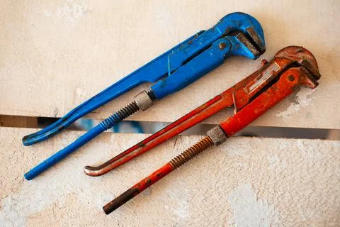 Close-up of two adjustable gas wrenches of red and blue color on wooden table. Stock Photos