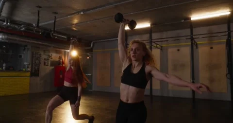 Close up of two athletic girls in light sportswear doing forward lunges with Stock Footage 313423474