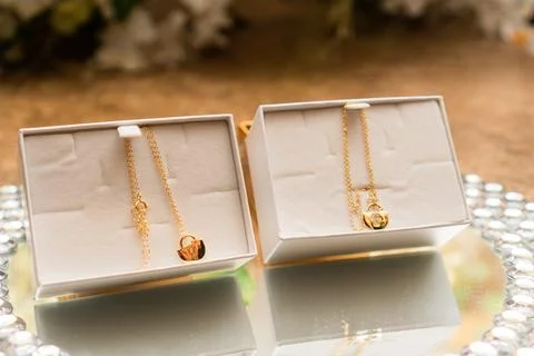 Close-up of two boxes with two gold necklaces with small jewels in shape of.. Stock Photos