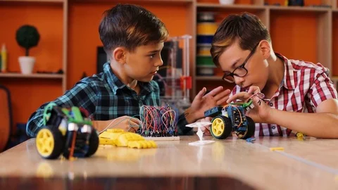 Close up of two boys managing to assemble robots with screwdrivers on the table 動画素材 82488654