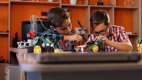 Close up of two boys using screwdrivers to assemble robotic machines on the Stock Footage 82409703