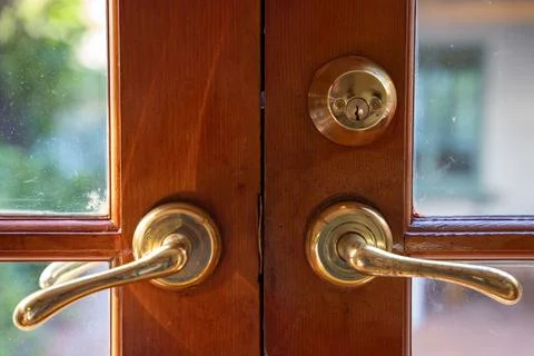 Close up on two brass door handles on a wooden door with window panes. Stock Photos
