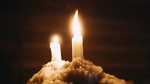 A close-up of two burning candles, the wax from which flows down solidifying Stock Footage 257058687