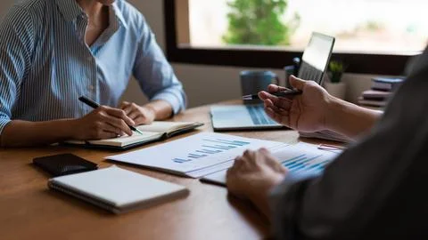 Close up of two business is reading document and writing notes while discus.. Stock Photos