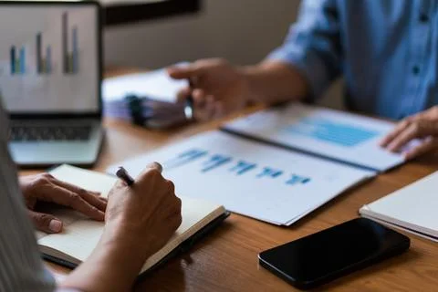 Close up of two business is reading document and writing notes while discus.. Stock Photos