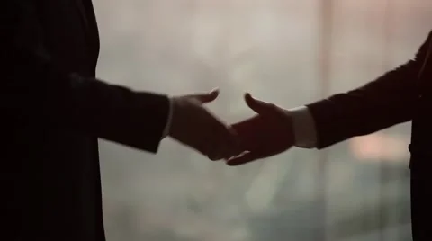 Close up of two businessmen shaking hands in a modern office. Silhouette shot. Stock Footage