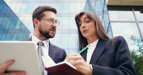 Close-up of two busy and confident business professionals standing near an Stock Footage 316771049