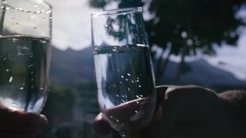 Close Up of Two Champagne Glasses Toasting Together with Scenic Nature Mountains Stock Footage 329933352