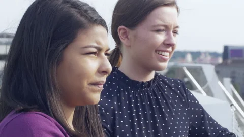 Close-up of two close friends watching cityscape on rooftop Stock Footage 133090534