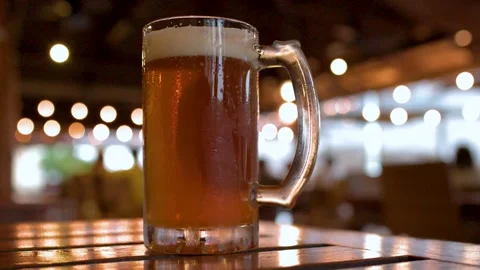 Close up of two cold glasses of draft beer on wooden table in outdoor cafe .. Stock Footage 333618550