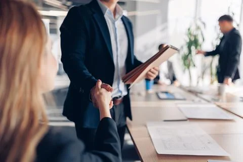 Close up of Two colleagues shaking hands while sitting in office before meeting Stock Photos