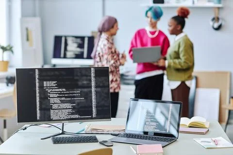 Close up of two computer screen with code lines and blurred creative team 写真素材