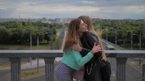 Close-up, two cute and laughing young women say goodbye to each other. Stock Footage 79413223