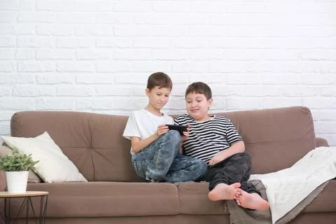 Close up of two cute boys using smartphone, looking at screen, childs holding Foto stock