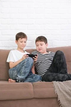 Close up of two cute boys using smartphone, looking at screen, childs holding Stock Photos