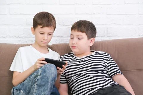 Close up of two cute boys using smartphone, looking at screen, childs holding Foto stock