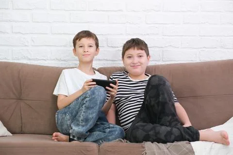 Close up of two cute boys using smartphone, looking at screen, childs holding Stock Photos