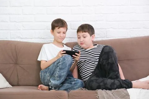 Close up of two cute boys using smartphone, looking at screen, childs holding Stock Photos