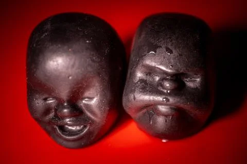 A close-up of two dark, sculptural faces placed face to face. Фото