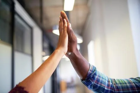 A close up of two diverse hands giving a hi-five celebration in the office Stock Photos