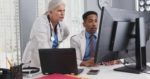 Close up of two doctors looking at computer monitor comparing notes Stock-Footage 98262463