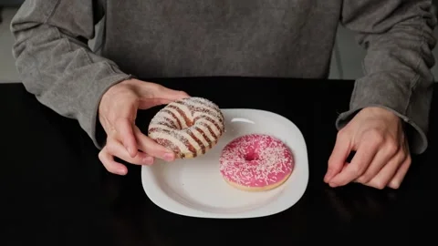 Close-up of two donuts on a plate as hands hesitate, touch, and examine them Stock Footage 305553966