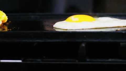 Close up two eggs fried on a black griddle with smoke Stock Footage 246553375