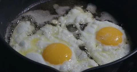 Close up of two eggs frying in oil in slow motion Stock Footage 319044415