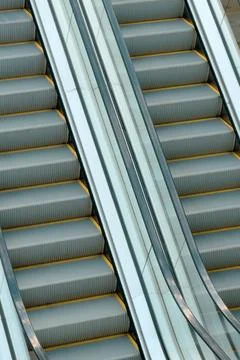 Close-up of two empty escalators with metallic sides and gray steps Stock Photos