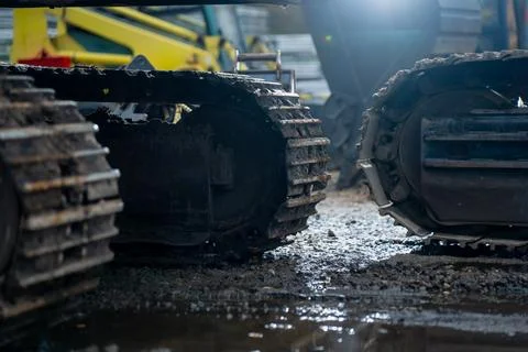 Close-up of two excavator crawler tracks on muddy construction surface Stock Photos
