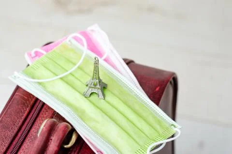 Close-up of two  face mask and  Tour eiffel miniature toy  on a suitcase for Stock Photos