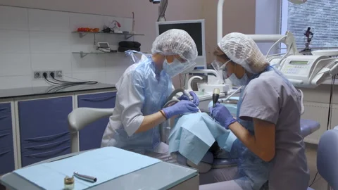Close-Up Of Two Female Dentists Performing Surgery On A Patient's Teeth Stock Footage 138062494