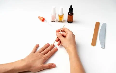 Close-up of two female hands using wooden cuticle stick for cuticle care and  Stock Photos