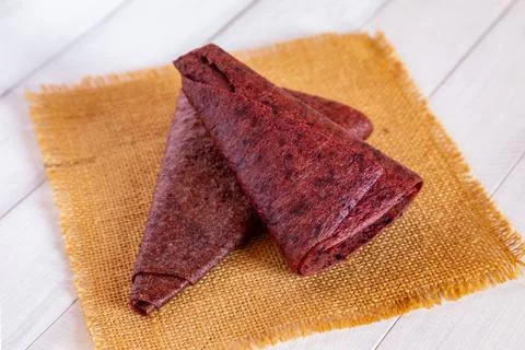 Close up of two folded red triangular fruit pastille pieces resting on yell.. Stock Photos