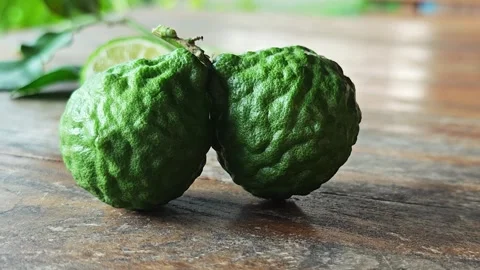 Close up of two fresh green kaffir lime fruits on wooden table. 스톡 동영상 339204605