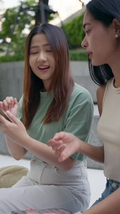 Close-up of two friends laughing and using a smartphone outdoors Stock Footage 292943189