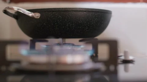 A close-up of two frying pans being placed on a lit stove. The preparation of Vidéo 255770608