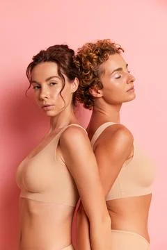 Close-up of two girlfriends inside the studio, stand back to back, lock their 스톡 사진