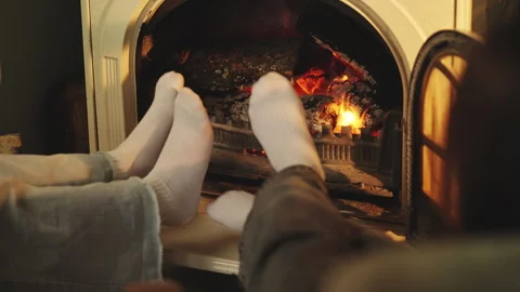 Close-up of two girls warm their feet by fireplace, enjoying winter holidays Stock Footage 343423765