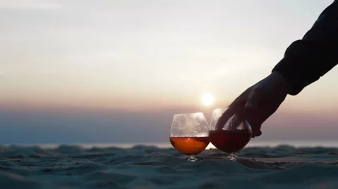 Close up of two glasses of brandy standing on the sand over incredible beach sun Stock Footage 49987722