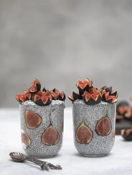 Close up two glasses of chia pudding decorated with fresh baby figs with spoon Stock Photos