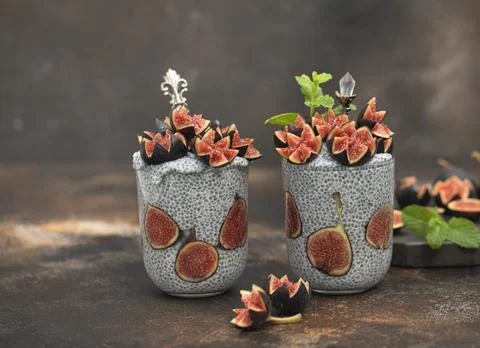 Close up two glasses of chia pudding decorated with fresh baby figs with spoon Stock Photos