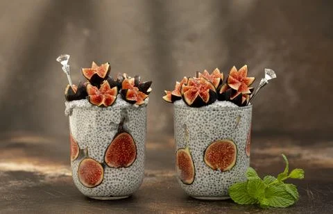 Close up two glasses of chia pudding decorated with fresh baby figs with spoon Stock Photos