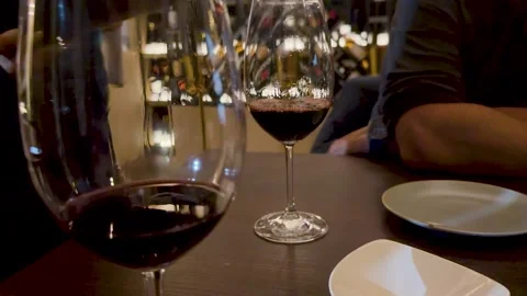 Close up of two glasses of red wine on a dark wooden table in restaurant se.. Vídeos de archivo 333224135